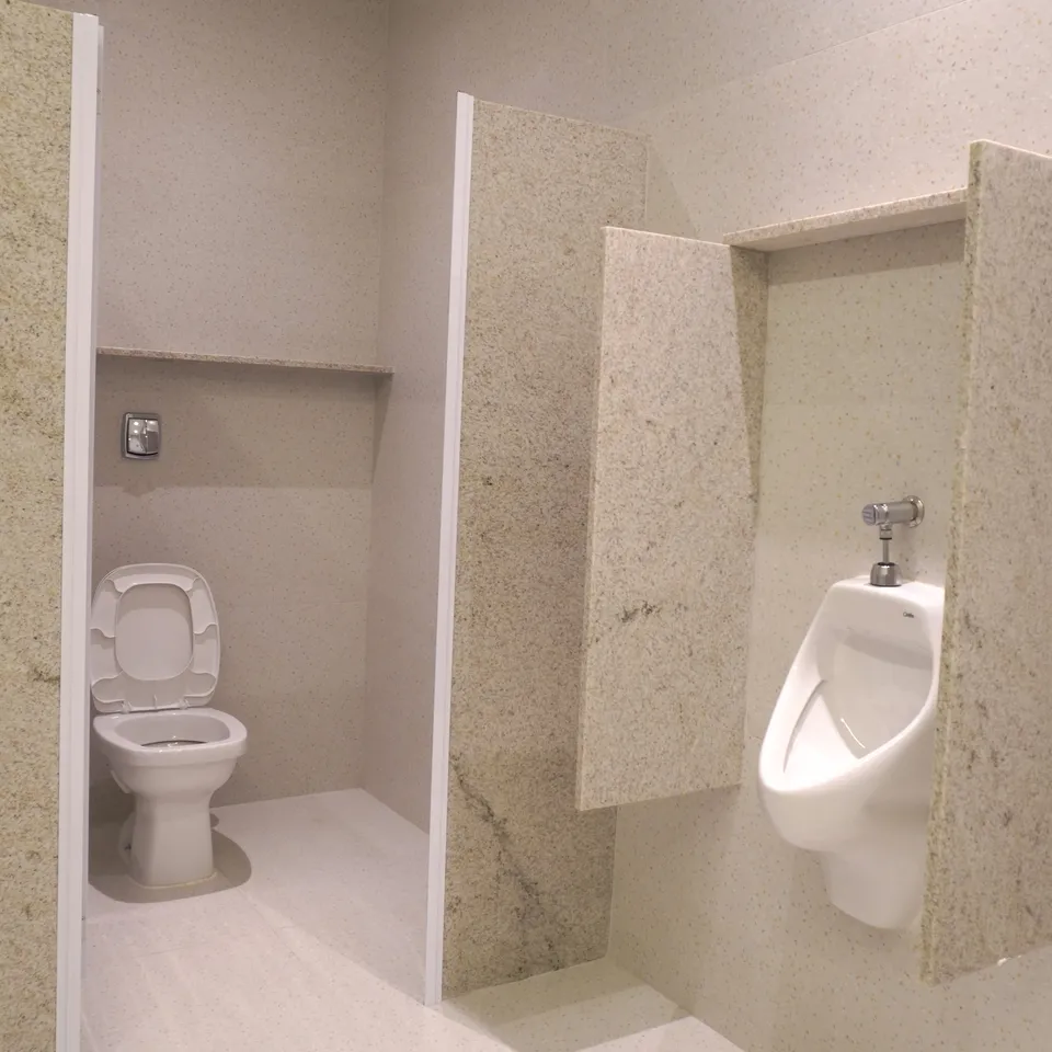 Cabines com divisórias de granito e mictório no banheiro da Piccolini Eventos