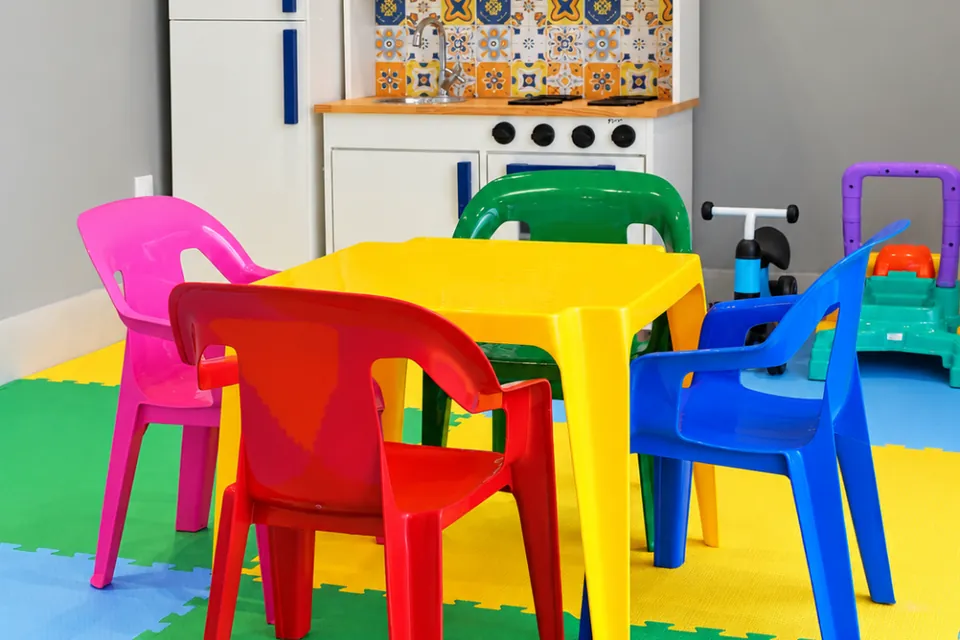 Mesinha com cadeiras coloridas na brinquedoteca da Piccolini Eventos, sobre piso de EVA
