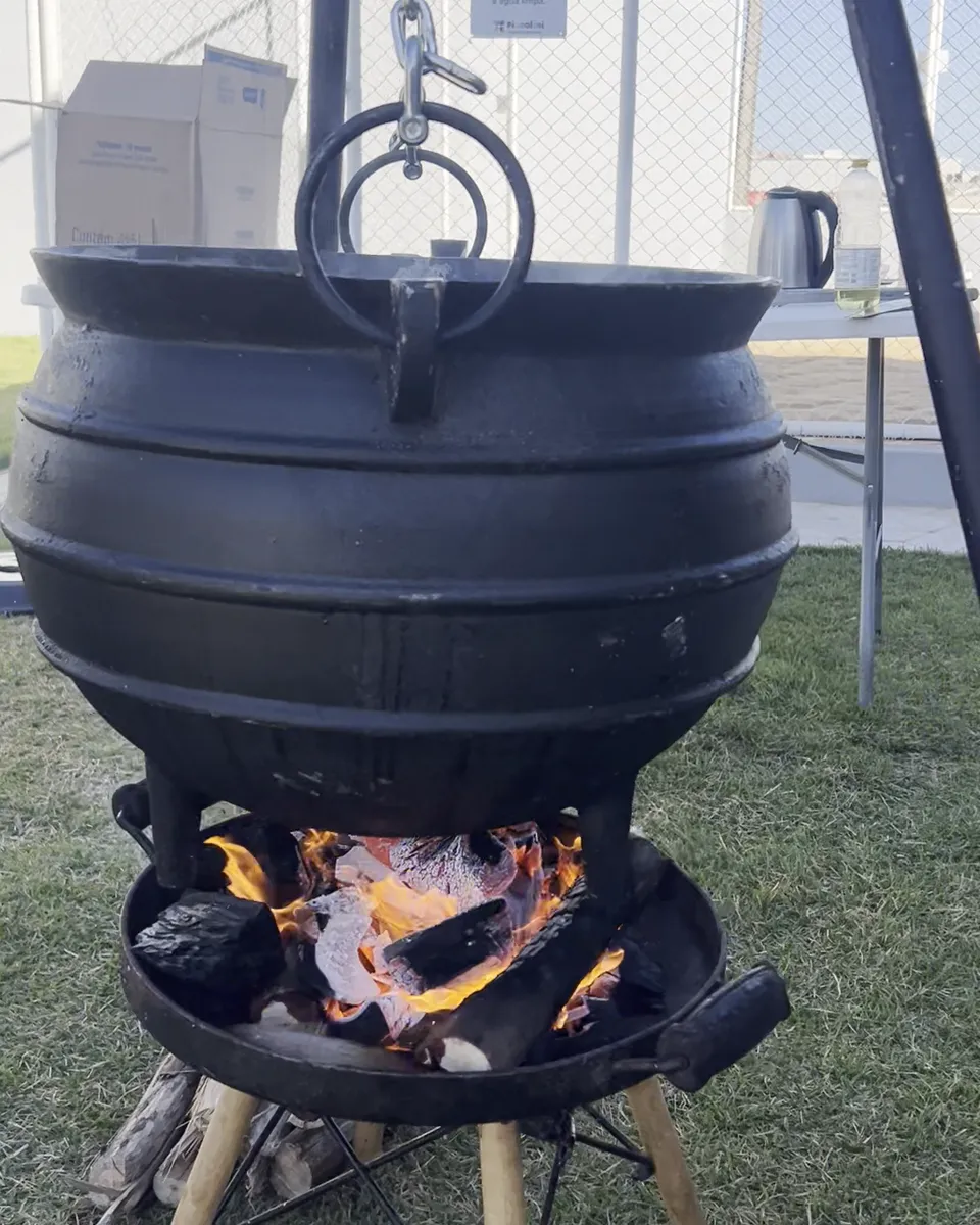 Caldeirão de ferro sobre o fogo no gramado da Piccolini Eventos, para confraternização