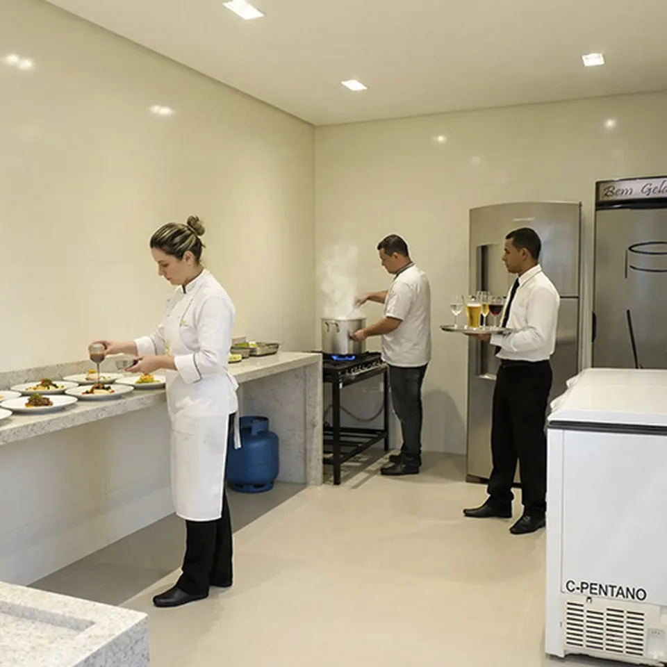 Equipe de garçons e chef finalizando pratos na cozinha da Piccolini Eventos
