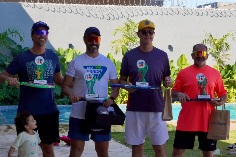 Vencedores do torneio de beach tennis da Piccolini com troféus ao lado da piscina