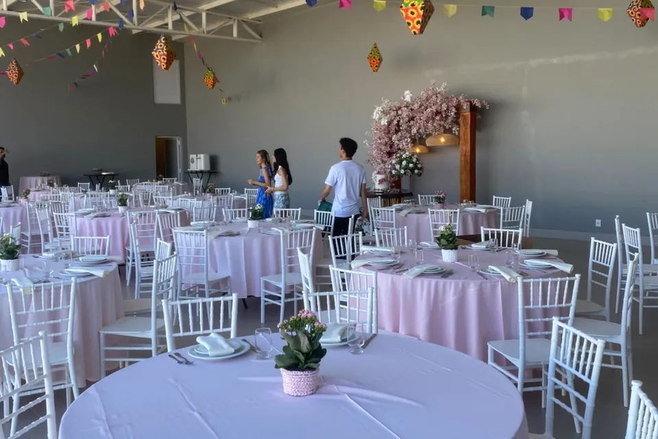 Salão da Piccolini Eventos com mesas redondas, toalhas rosa e cadeiras brancas, em Goiânia