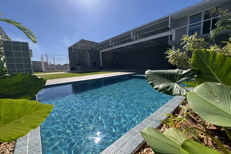 Piscina aquecida da Piccolini Eventos com sol e plantas ao redor, em Goiânia