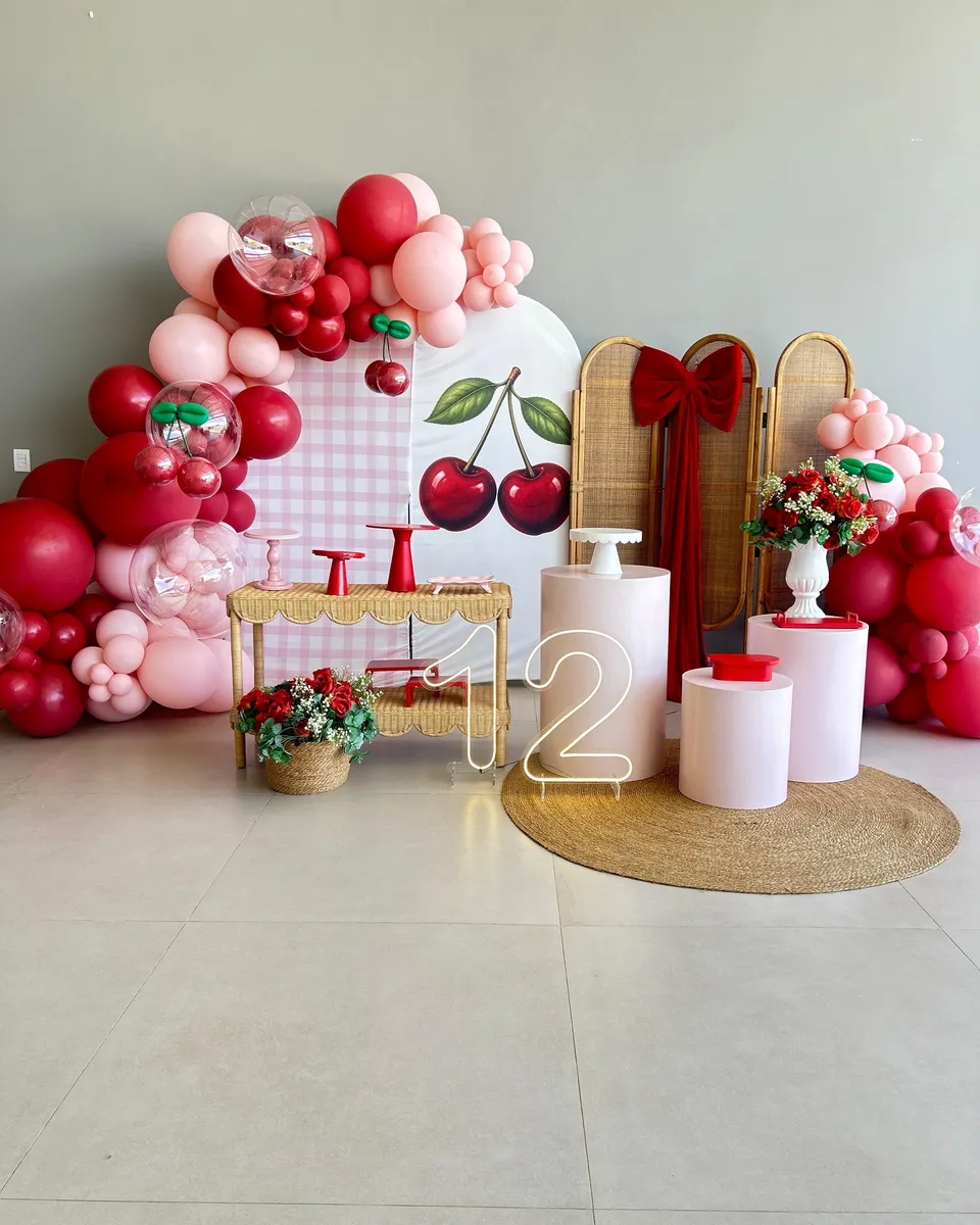 Painel de aniversário de 12 anos com tema cerejas, balões vermelhos e rosa e número em neon na Piccolini Eventos