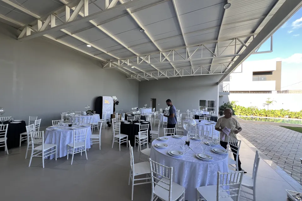 Salão da Piccolini Eventos com mesas redondas e cadeiras brancas montadas para evento, em Goiânia